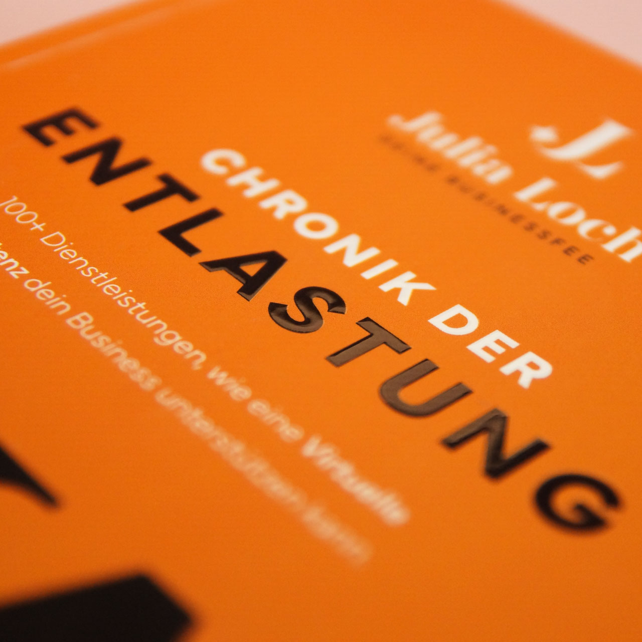 Nahaufnahme des Bucheinbands mit glänzendem Relieflack auf dem Wort „Entlastung“ auf mattem orangefarbenem Hintergrund