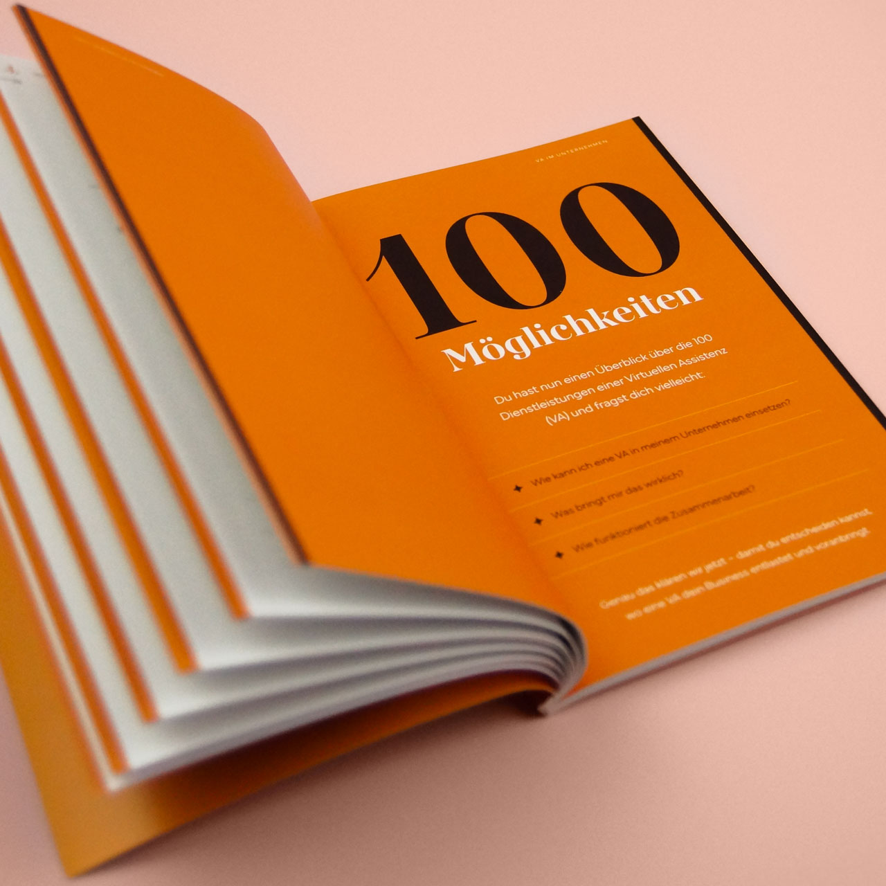 Offen liegendes Buch „Chronik der Entlastung“ mit orangefarbener Doppelseite und der Zahl „100“ in großer Typografie