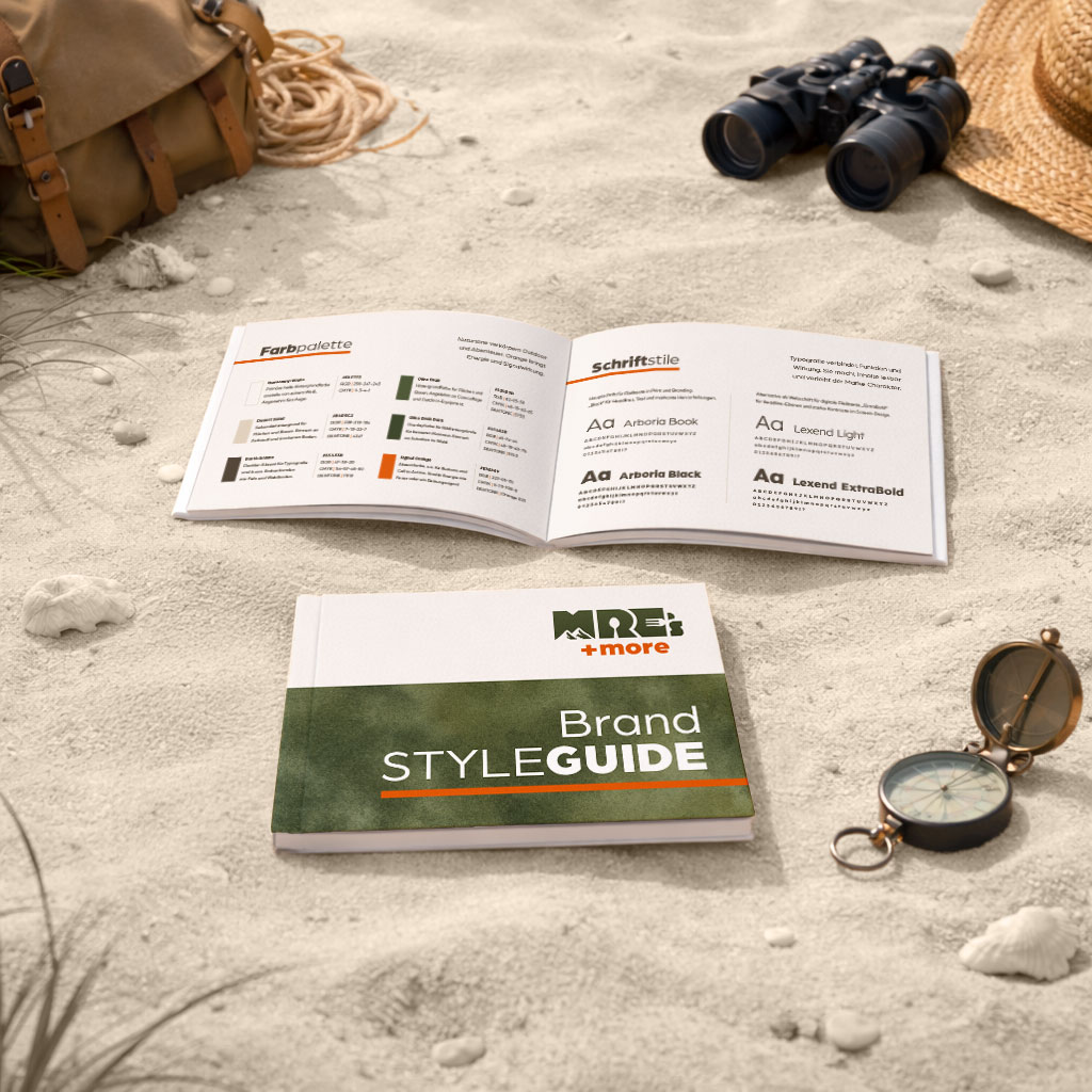 Brand Styleguide MRE's & more aufgeschlagen auf Sand mit Kompass und Fernglas, zeigt Seiten mit Farbpalette und Typografie